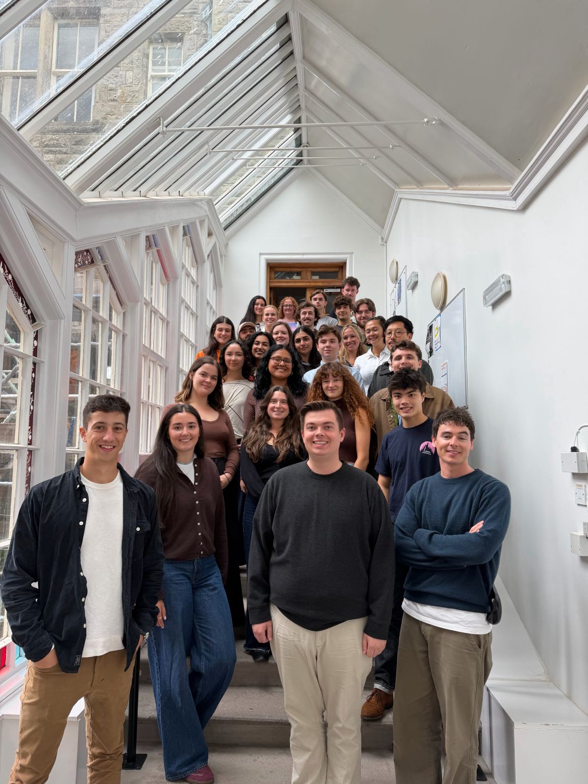 Members of the first Master of Public Policy cohort at the University of St Andrews gathered on an indoor staircase.